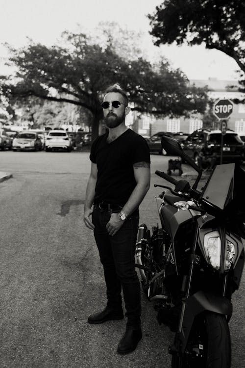 A man in sunglasses standing next to a motorcycle