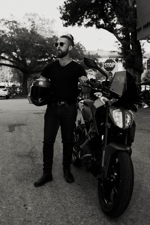 A man in a black shirt and sunglasses standing next to a motorcycle