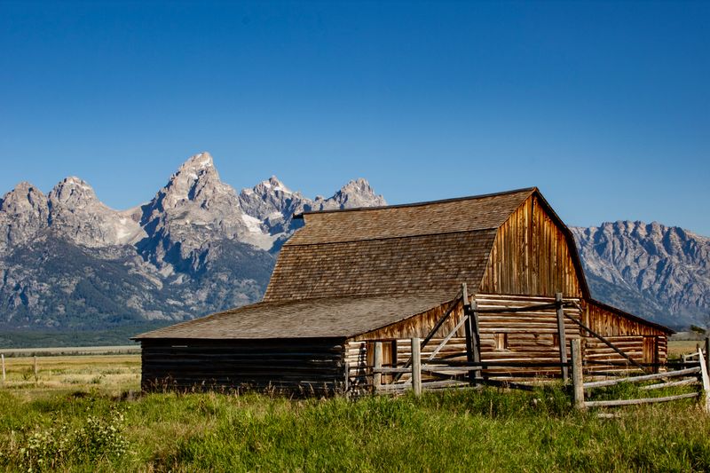 Stone Fox Setting Rustic Barn in Wyoming with Mountain Backdrop · Free Stock Photo