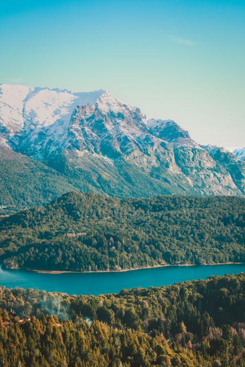 Free Stunning landscape of snowcapped mountains and lush forests overlooking a serene lake in Bariloche, Argentina. Stock Photo
