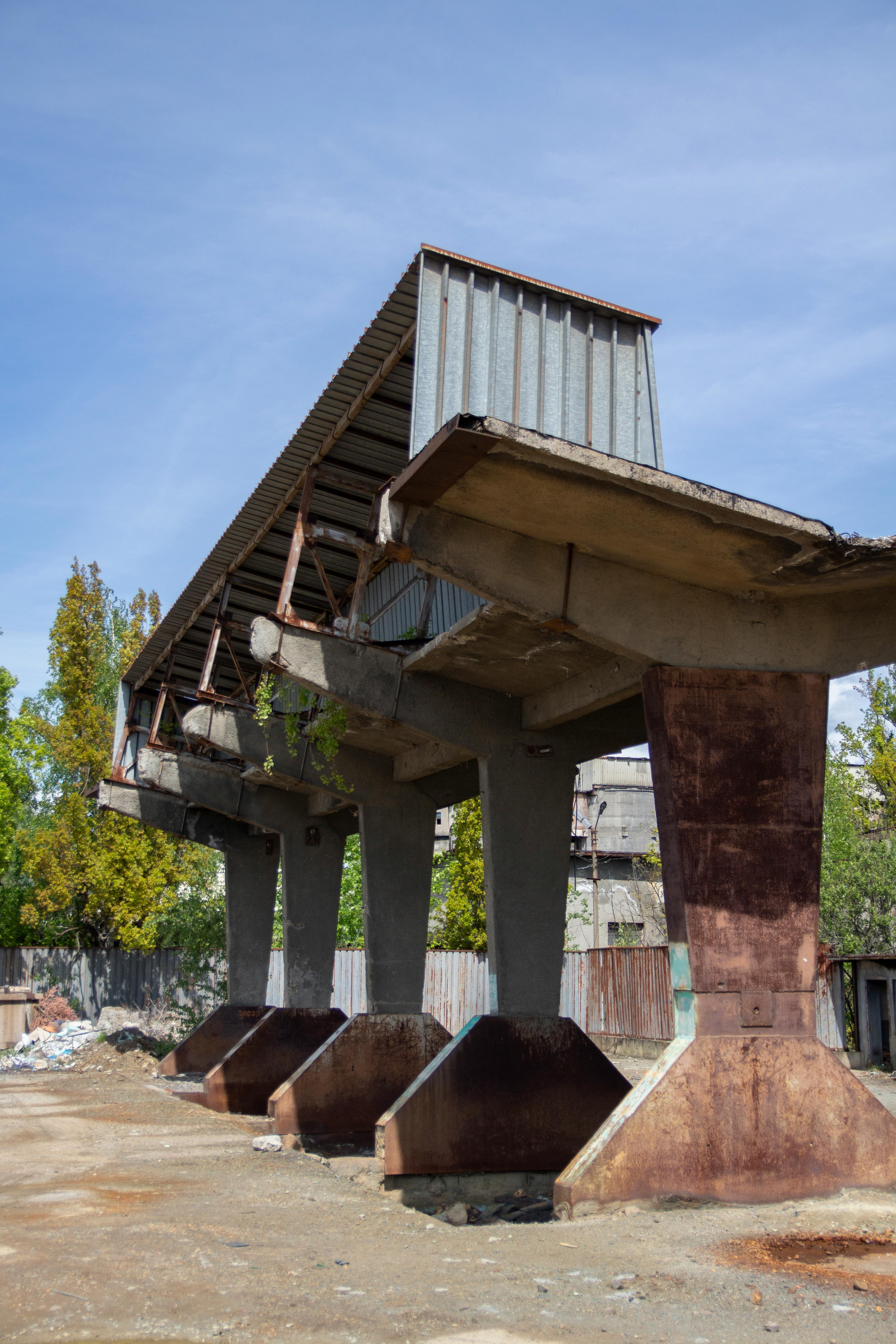 ingyenes Egy üres, pusztuló ipari építmény betonoszlopokkal és fémtetővel kültéri környezetben. Stockfotó