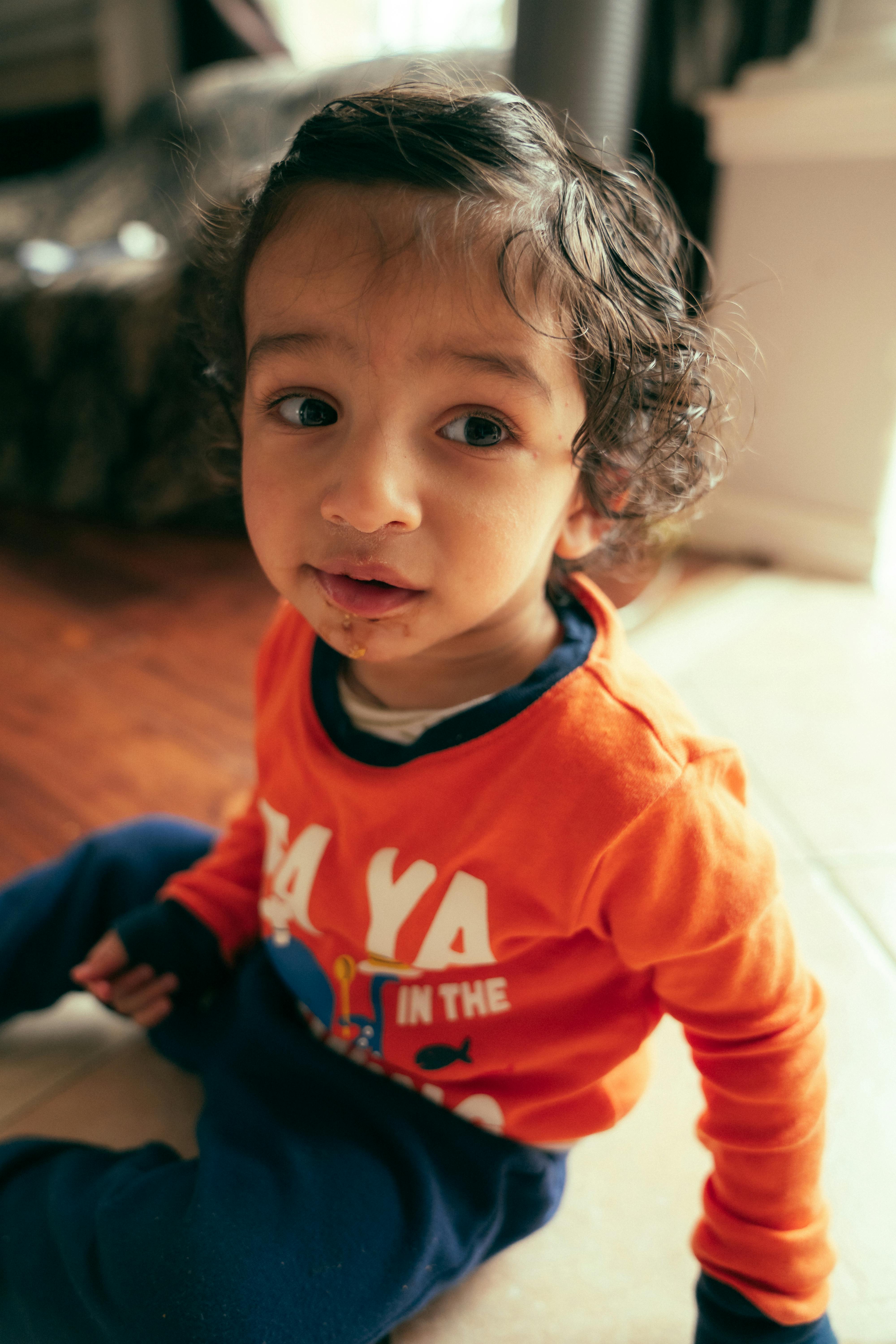 a little boy sitting on the floor in a house