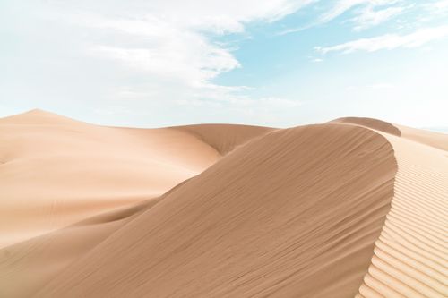 Free A serene view of vast sand dunes under a clear blue sky, capturing desert tranquility. Stock Photo