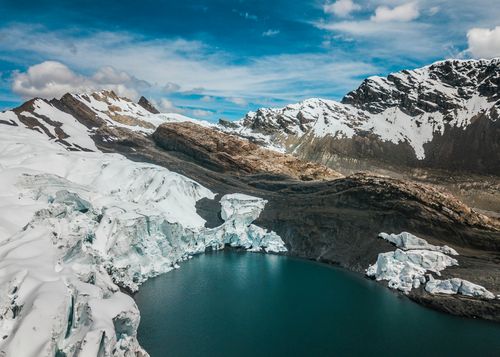 Free A breathtaking aerial view of the Andes with glaciers surrounding a turquoise lake under a vibrant blue sky. Stock Photo