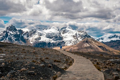 Free A person walking down a path in front of a mountain range Stock Photo