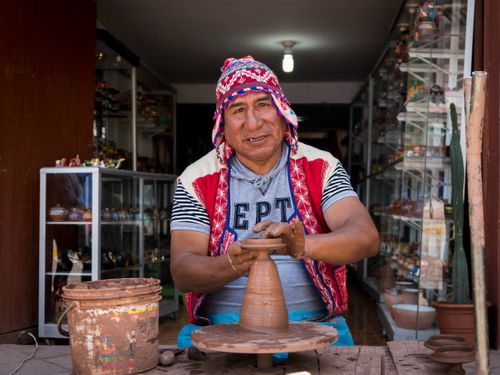 Free A potter in traditional attire crafting clay pottery in a Peruvian workshop. Stock Photo