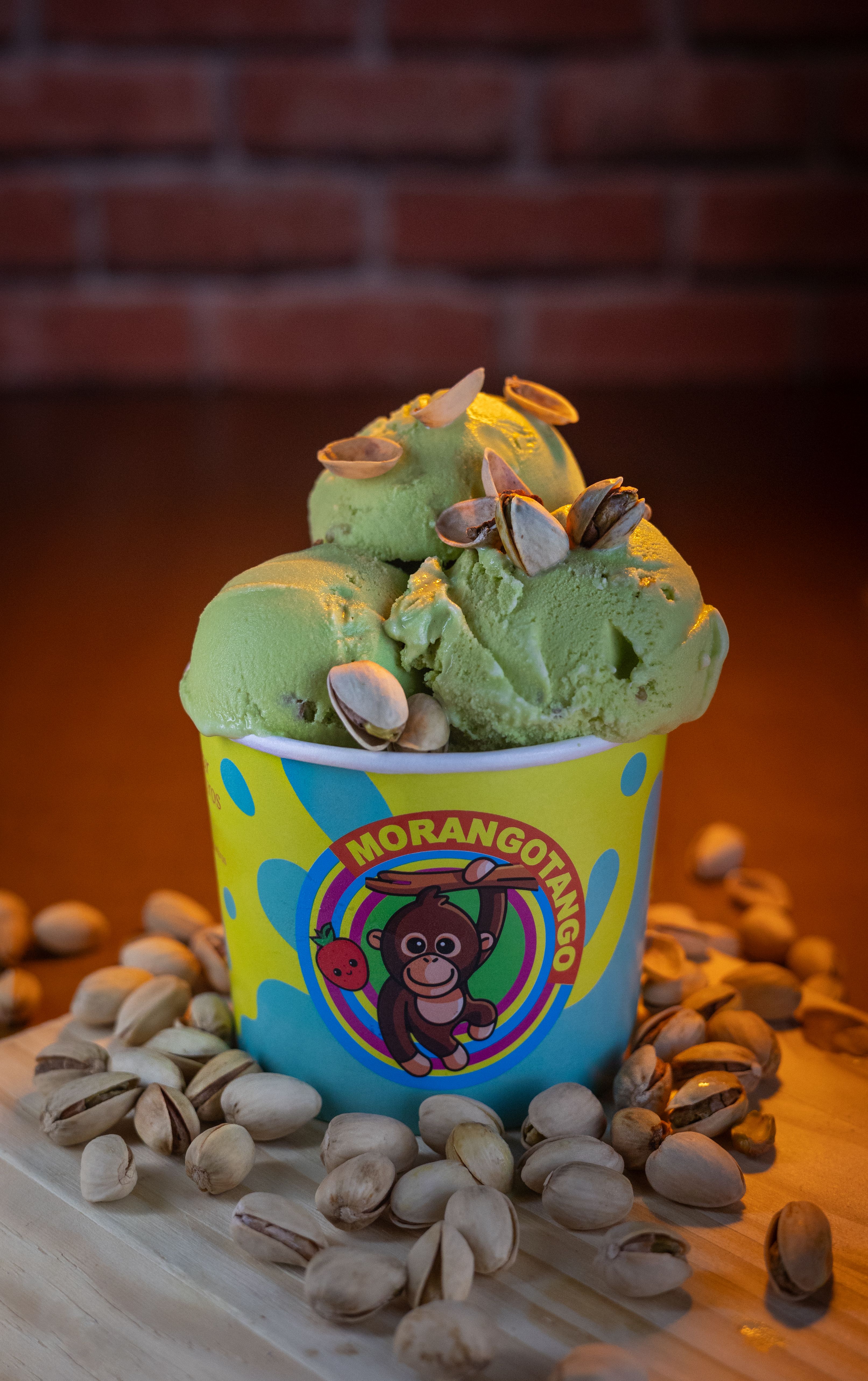 Tasty pistachio ice cream served in a colorful cup with scattered nuts.
