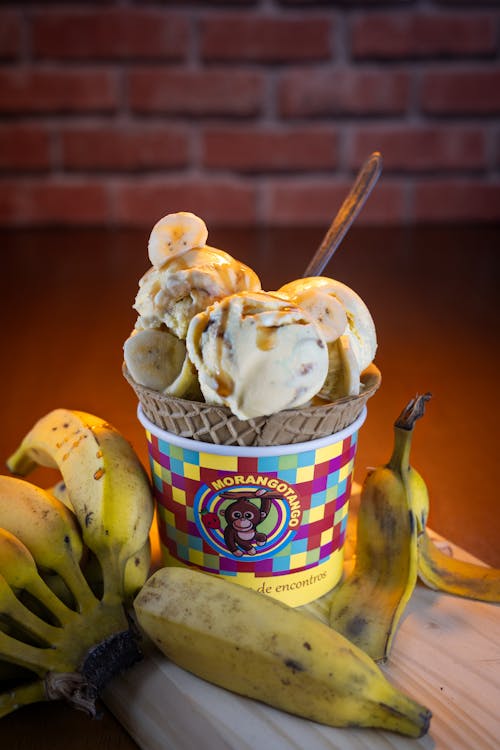 A bowl of ice cream with bananas and a spoon
