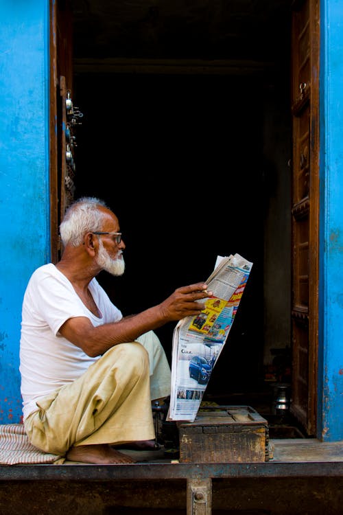 신문 기사를 들고 앉아있는 노인