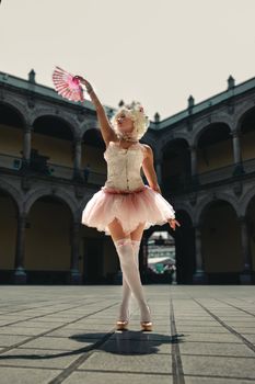 Ballerina in a vintage costume poses gracefully in a historic Mexico City courtyard.