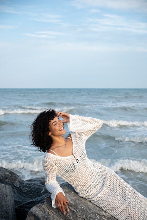 Smiling Woman Lying Down on Rock on Sea Shore