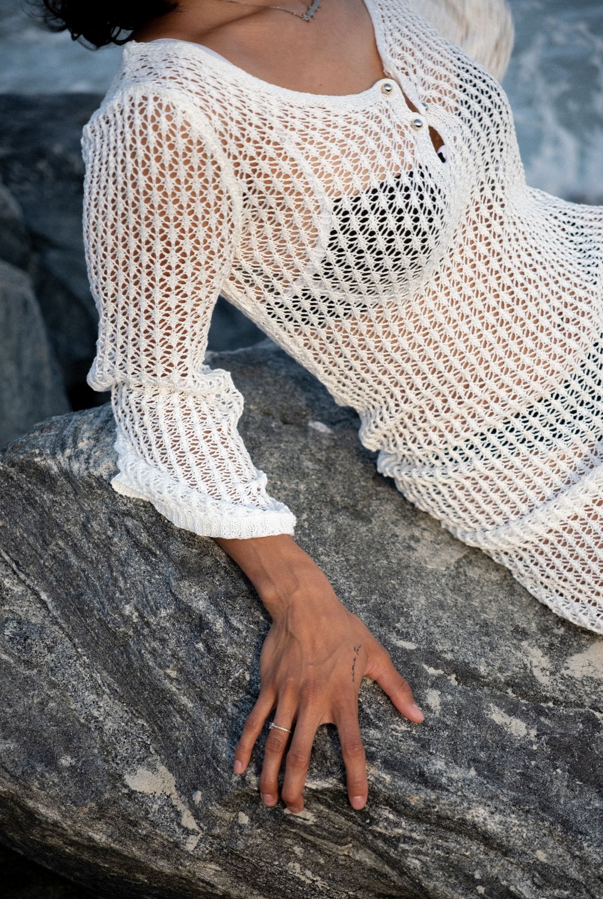 A woman in a translucent dress on a boulder by the sea, the elegant resort throw-on
