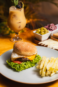 Delicious cheeseburger with fries and a refreshing drink served on a restaurant table.