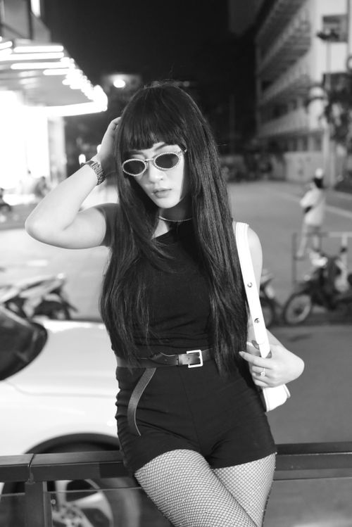Free Young woman in sunglasses poses confidently at night in a city. Fashionable and modern style. Stock Photo