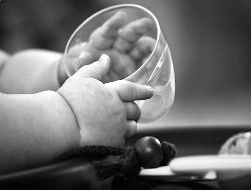 A baby's hand holding a glass cup
