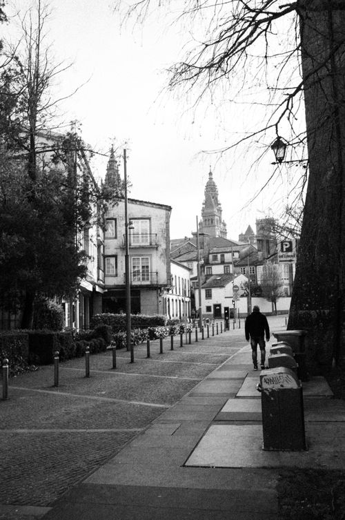 Free A black and white view of Santiago de Compostela's city street with lone pedestrian and iconic architecture. Stock Photo
