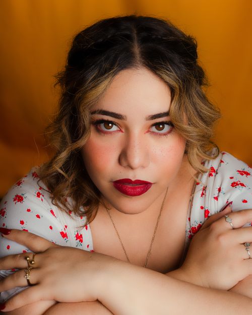 Free Close-up portrait of a woman with red lipstick and crossed arms, set against a vivid yellow background. Stock Photo