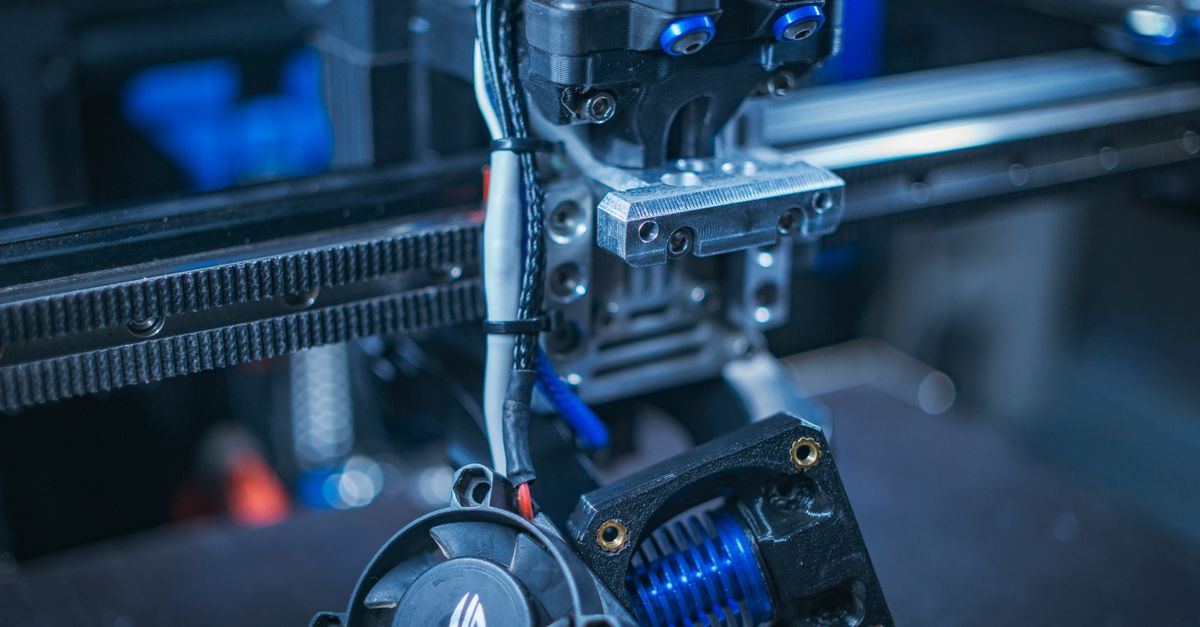 Detailed view of a 3D printer showcasing components like wires, gears, and cooling fan.