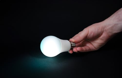 Hand holding glowing light bulb.