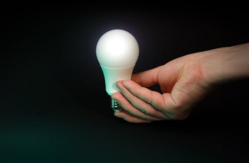 Hand holding glowing light bulb.