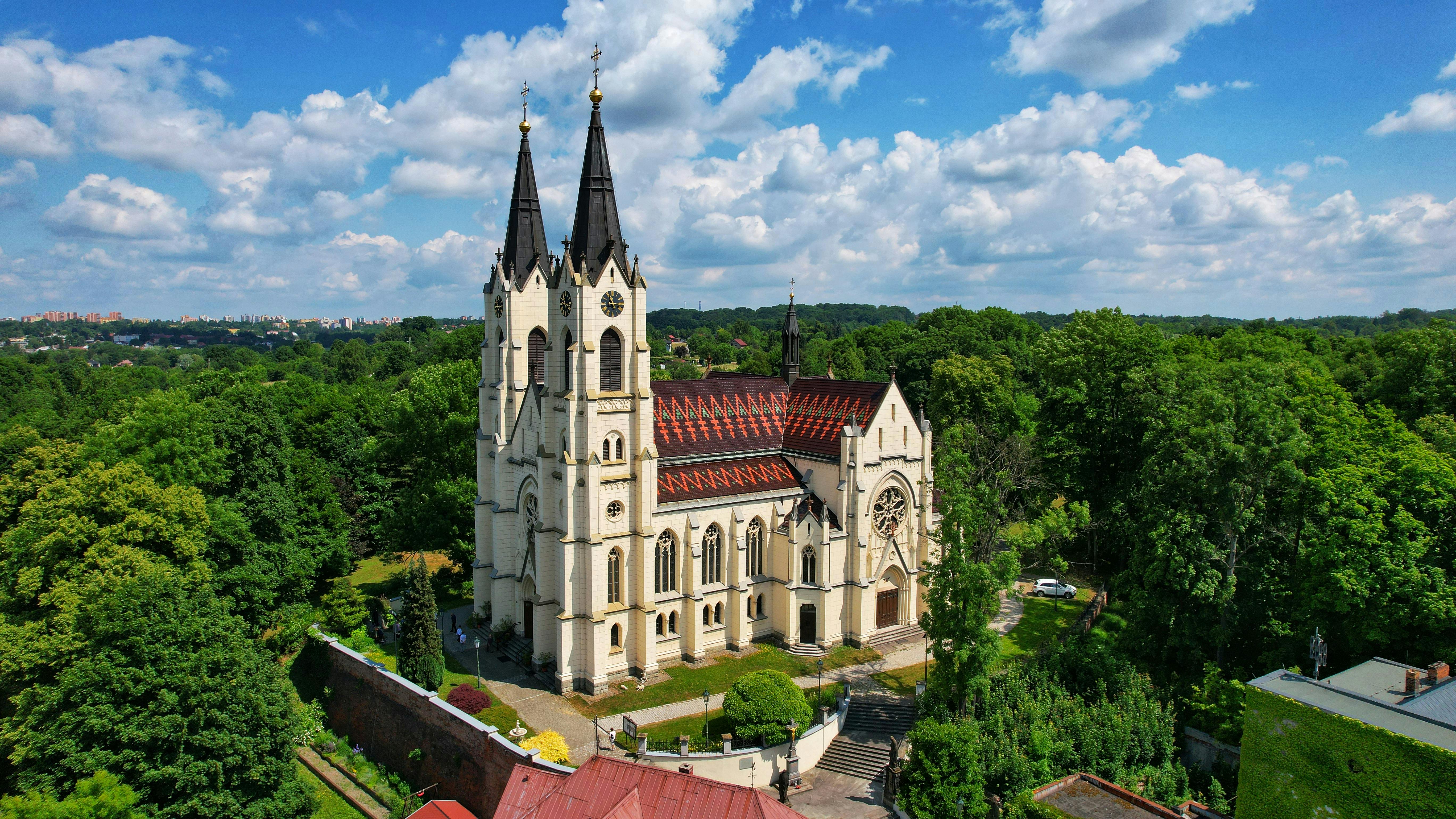 Stunning aerial view of a historic church surrounded by lush greenery in Orlová, Česko.
