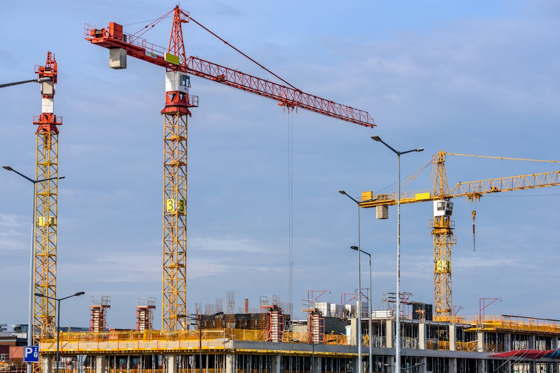 Free Three Yellow and Red Tower Cranes Under Clear Blue Sky Stock Photo