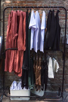 乡村砖墙旁的衣架上，整齐地挂着多样化的服装系列，展现了时尚的多样性