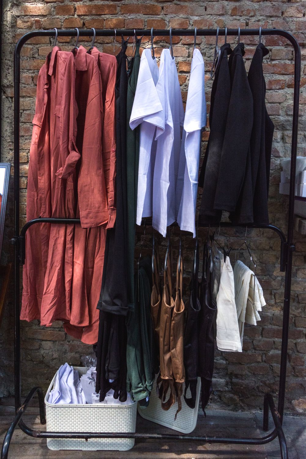 Garments displayed on a rack against a brick wall