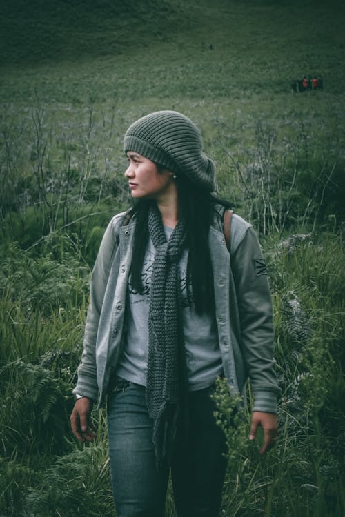 Woman Walking on Green Field Looking Her Right Side