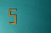 抽象照片中，青色背景上有一个金色的数字五，并带有负空间