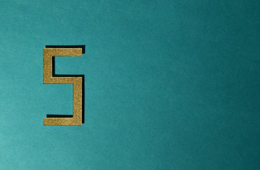 抽象照片中，青色背景上有一个金色的数字五，并带有负空间