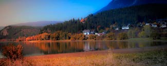 不列颠哥伦比亚省鲑鱼臂湖上的倒影，映衬着美丽的秋季景观，突出了充满活力的树叶和宁静的水域