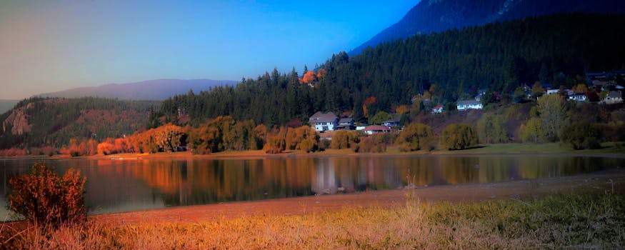 不列颠哥伦比亚省鲑鱼臂湖上的倒影，映衬着美丽的秋季景观，突出了充满活力的树叶和宁静的水域