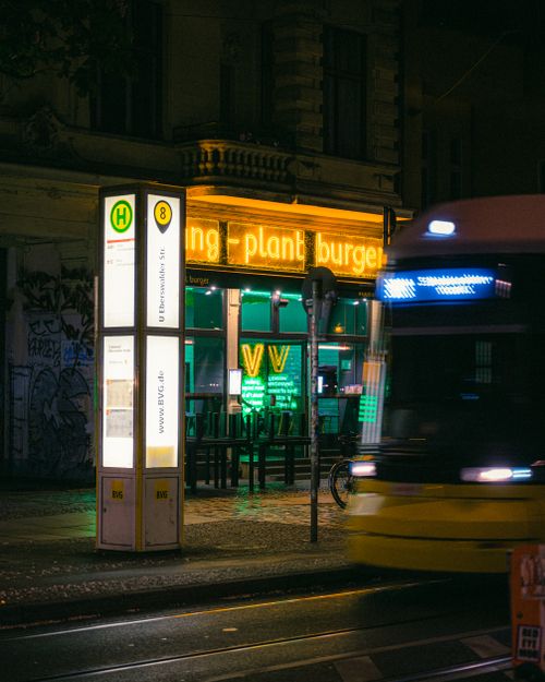Free A nighttime street scene in Berlin featuring a passing tram and an illuminated bistro. Stock Photo