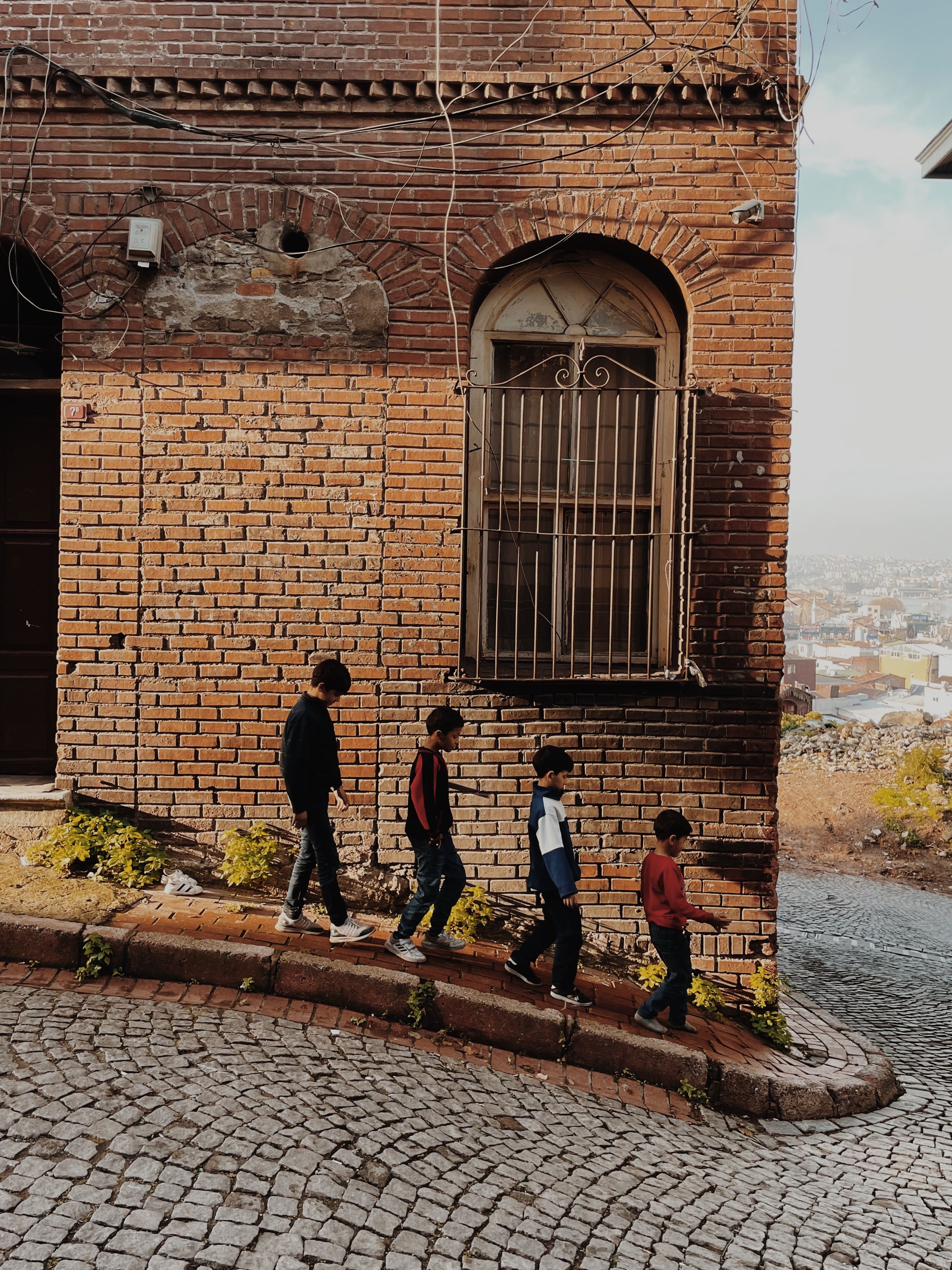 Four kids walking down a cobblestone street beside an old brick building on a sunny day - school district licensing