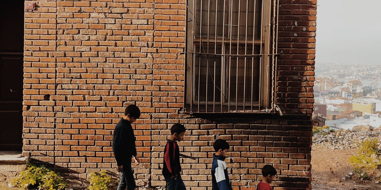Four kids walking down a cobblestone street beside an old brick building on a sunny day - school district licensing