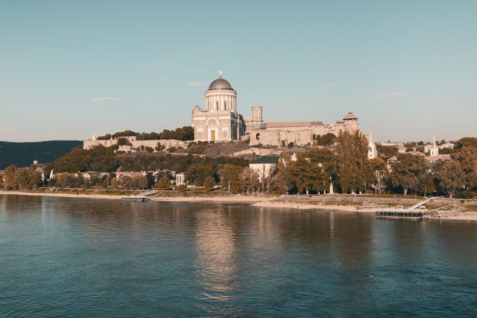 Fotomural Impresionante vista de la Basílica de Esztergom en Hungría, reflejándose en el río bajo un cielo despejado.