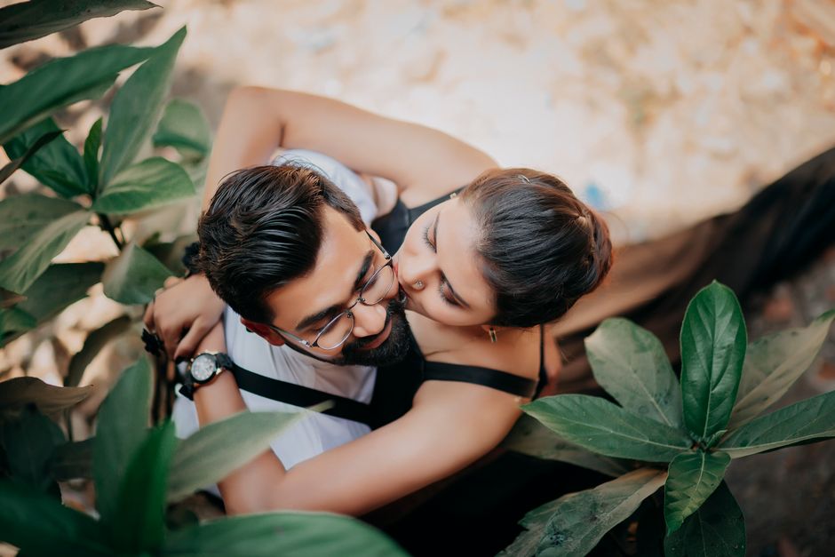 A loving couple embraces amidst lush greenery, captured from above, exuding warmth and affection.