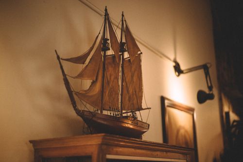Free A beautifully crafted vintage sailboat model displayed in a warm, cozy indoor space with a nostalgic ambiance. Stock Photo