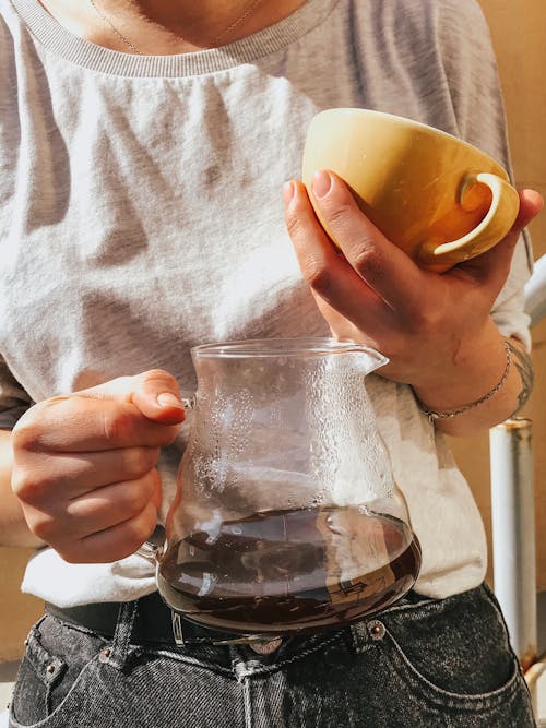 Free Close-up Photo of Woman Holding Glass Pitcher of Coffee and a Ceramic Mug Stock Photo