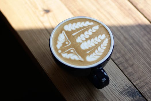 木桌上的咖啡杯里，盛着制作精美的拿铁艺术