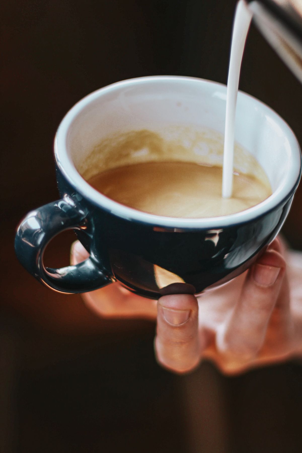 Chorro de leche vertido sobre una taza de café, un gesto que rompe el ayuno intermitente