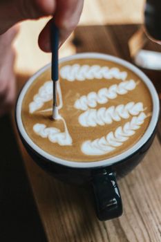 Close-up of a barista crafting intricate latte art in a cozy coffee shop setting.