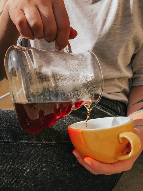 Free Person pouring hot coffee into a yellow mug, capturing the rich aroma and texture. Stock Photo