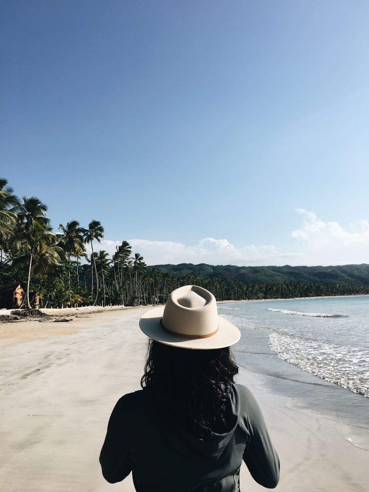 Traveller in a sun hat walking along the beach in Las Terrenas, Samaná
