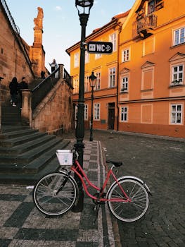 在风景如画的鹅卵石广场上，一辆老式自行车停在那里，沐浴着黄金时段的灯光，周围环绕着历史悠久的建筑