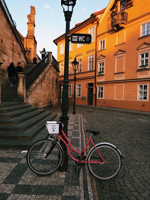 A vintage bicycle parked in a picturesque cobblestone square with golden hour lighting and historic architecture.