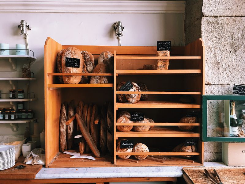 A charming bakery scene featuring assorted breads on wooden shelves with rustic decor.