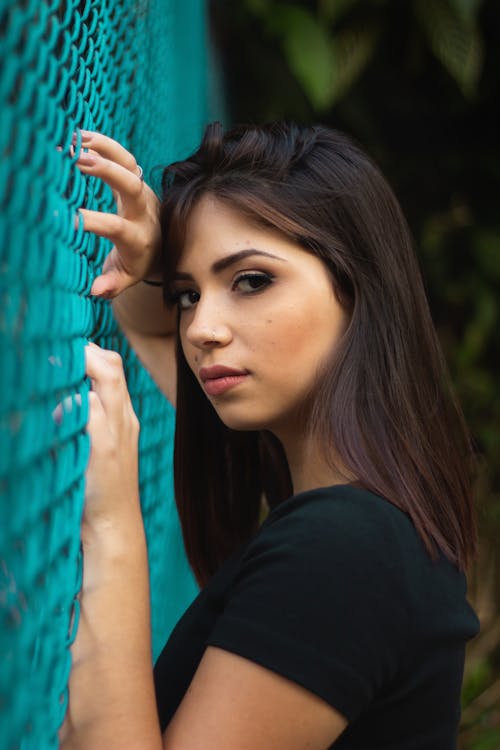 Mulher Tocando A Cerca De Arame De Metal Azul Vestindo Uma Camisa Preta