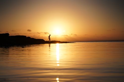 Free A lone silhouette walks along Currarong Beach at sunset, reflecting on serene waters. Stock Photo